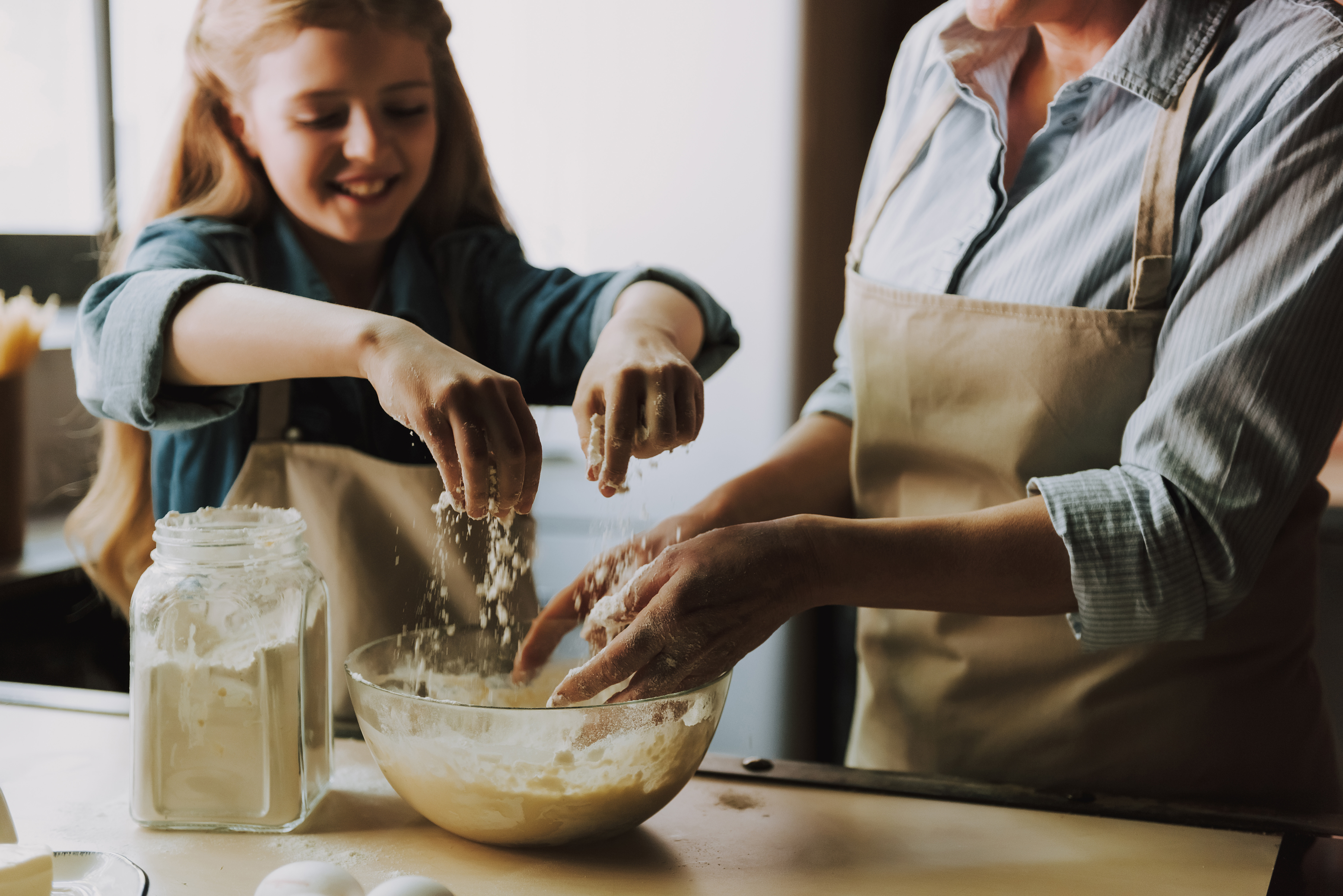 Kind und Elternteil backen zusammen mit Backzutaten